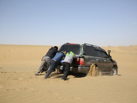 车子陷进沙中，大家要合力推车。