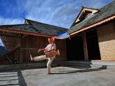 一邊擊打象腳鼓一邊跳舞的傣族人。