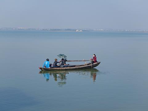 在湖中拍攝漁歌傳承人撐船唱歌。